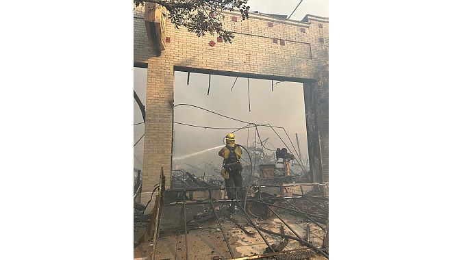 A firefighter hoses down Steve's Bike Shop. Steve Salinas photo. 